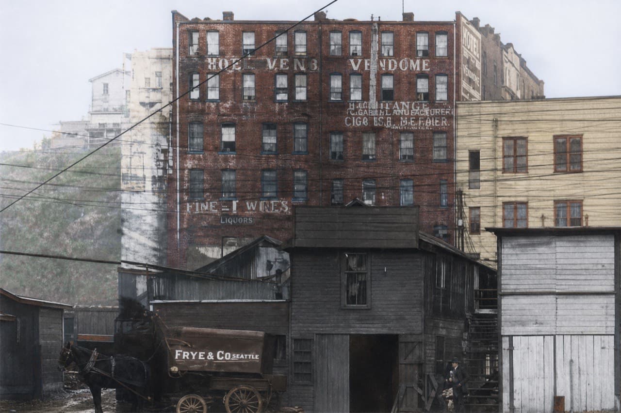 AI-colorized restoration of the rear facade of the Hotel Vendome in 1908, seen from the waterfront, with sheds and a Frye and Co wagon below the brick wall
