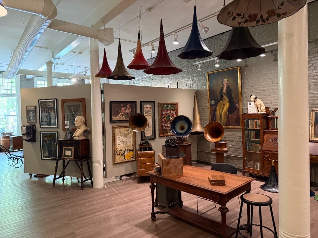 A wall of gramophones, horns, framed works, and antique objects in the Beautiful Things exhibition.