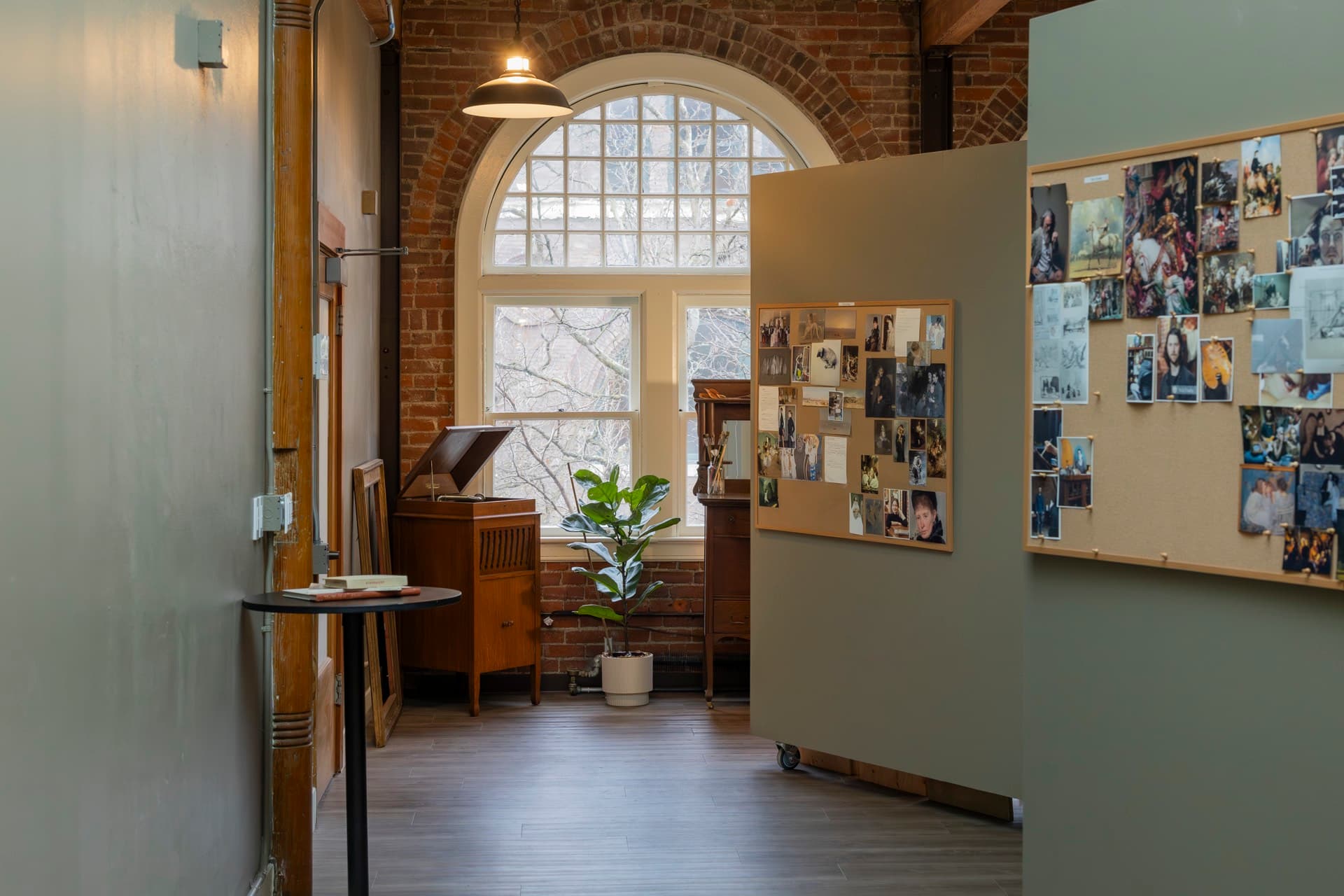 A tall arched north-light window in the upstairs studios, brick walls and wood floors